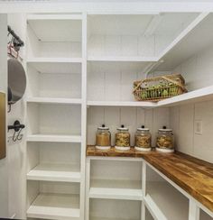 an empty pantry with white shelves and wooden counter tops