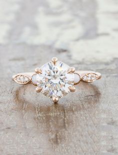 an antique style engagement ring with three stones on the band and a center stone in the middle