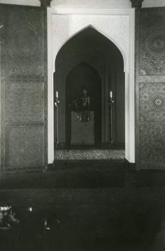 an old black and white photo of a man standing at the entrance to a building