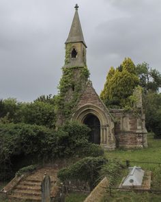 an old church with a steeple surrounded by greenery