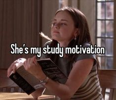 a woman sitting at a table with an open book in her hand and the words she's my study motivation