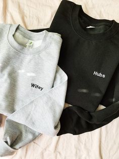 two sweatshirts sitting on top of a bed next to each other with the word hubs printed on them