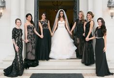 a group of women standing next to each other in front of a door wearing black dresses