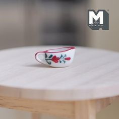 a small red and white bowl sitting on top of a wooden table