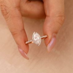 a woman's hand holding an engagement ring with a pear shaped diamond on it