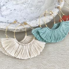 three pairs of earrings with tassels hanging from the hoop on top of each other