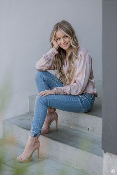 a woman sitting on some steps with her legs crossed and wearing high heeled shoes