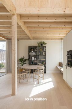 an open kitchen and dining area with wooden ceilinging, white walls, and wood flooring