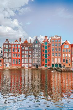 several buildings are reflected in the water on a sunny day with blue sky and white clouds