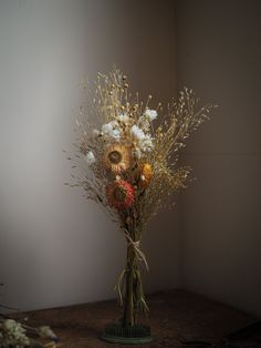 a vase filled with lots of flowers sitting on top of a wooden table next to a wall