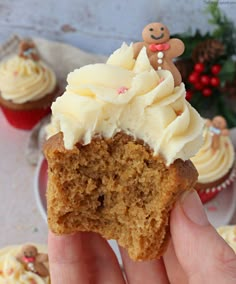 a person holding up a cupcake with frosting on it and a gingerbread man figurine