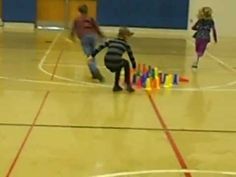 three children playing with plastic cups on a basketball court