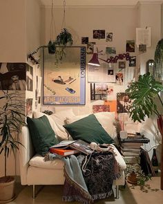 a living room filled with lots of plants and pictures hanging on the wall above it