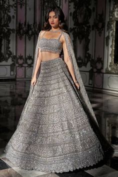 Silver lehenga featuring delicate sequin embroidery in geometric pattern and attached cancan. Paired with a strappy padded blouse with crystal drops at the waist and dupatta with a border and overall jaal in a matching pattern. Components: 3 Pattern: Embroidered Type Of Work: Sequin, Crystal Neckline: Sweetheart Sleeve Type: Sleeveless Fabric: Net Color: Silver Other Details:  Attached cancan Padded blouse Tasseled hem blouse Lehenga length: 45 - 46 inches Occasion: Sangeet, Reception - Aza Fashions Silver Lehenga, Tulle Lehenga, Seema Gujral, Sweetheart Bridal, Kurta Lehenga, Blouse Lehenga, Scalloped Blouse, Pattern Outfits, Reception Look