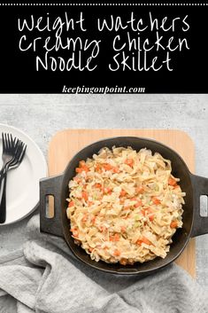 a skillet with noodles and carrots in it on a cutting board next to a plate