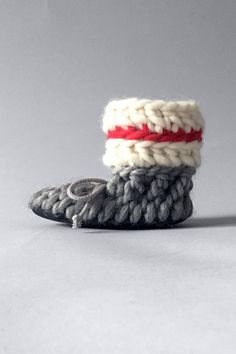 two knitted shoes sitting on top of each other next to one another with red and white bands