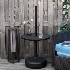 a black table with two vases on it next to a chair and wooden fence