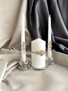 three candles sitting on top of a white cloth