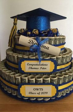 a graduation cake made out of dollar bills and diplomas with blue ribbon on top