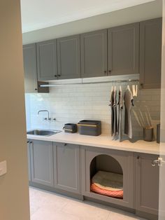 a kitchen with gray cabinets and white counter tops, including a dog bed in the middle