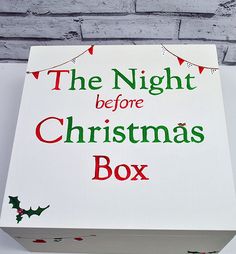 the night before christmas box is on display in front of a white brick wall with red and green lettering