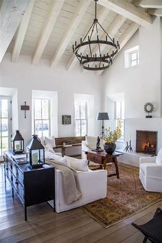 a living room filled with furniture and a chandelier hanging from the ceiling over a fire place