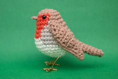 a small crocheted bird sitting on top of a green surface