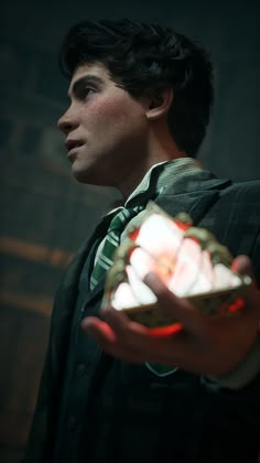 a man in a suit and tie holding a small object with light coming from it