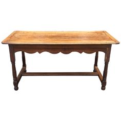 an old wooden table with scalloped legs and a long shelf on one end