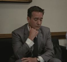 a man in a suit and tie sitting at a table with his hand on his chin