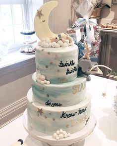 a three tiered cake is decorated with stars and the moon on it's side