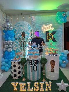 a man standing in front of a cake table with balloons and decorations on the wall