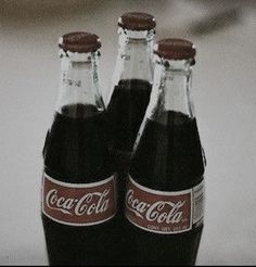 two coca - cola bottles sitting on top of a white table next to each other