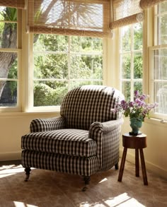 a chair sitting in front of a window next to a table with flowers on it