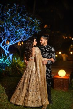 a man and woman standing next to each other in front of a tree at night