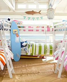 bunk beds with surfboards on them in a room that has white walls and wood flooring