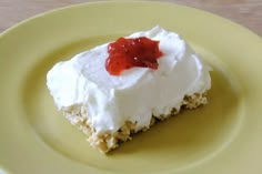 a piece of cake with white frosting and red jelly on top sitting on a yellow plate