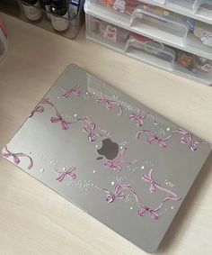 an apple laptop computer with pink bows on it's back and side cover, sitting on a desk