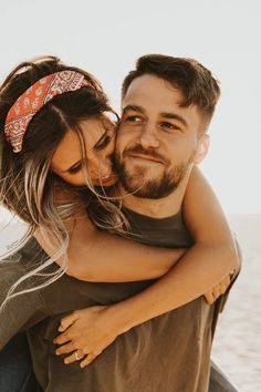 a man and woman hugging each other on the beach