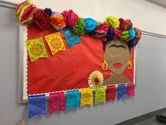 a bulletin board decorated with colorful paper flowers and cutouts on the front, along with an african woman's face