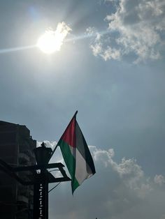 the sun shines brightly behind a flag on top of a pole in front of a building