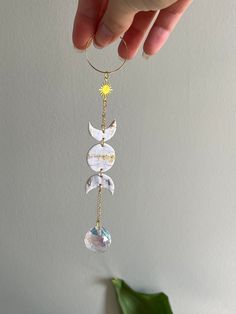 a hand holding a glass ornament in the shape of a sun and moon