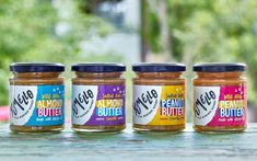 three jars of peanut butter sitting on top of a wooden table