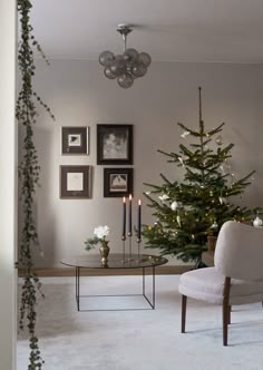 a living room with a christmas tree in the corner and pictures hanging on the wall