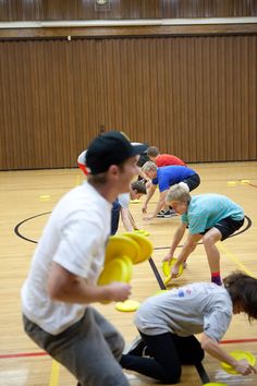 a group of people playing with frisbees in an indoor gym floor area