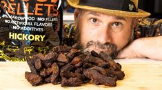 a man leaning on a table next to a bag of nuts and a pile of chocolate