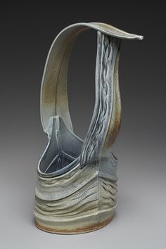 a sculpture made out of metal with wavy lines on the bottom and sides, sitting in front of a gray background