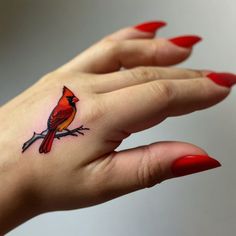 a woman's hand with a red bird tattoo on it