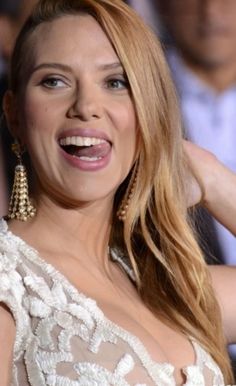 a close up of a person with a smile on her face and wearing large earrings