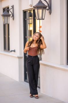 a woman standing on the sidewalk in front of a building with her hair blowing back